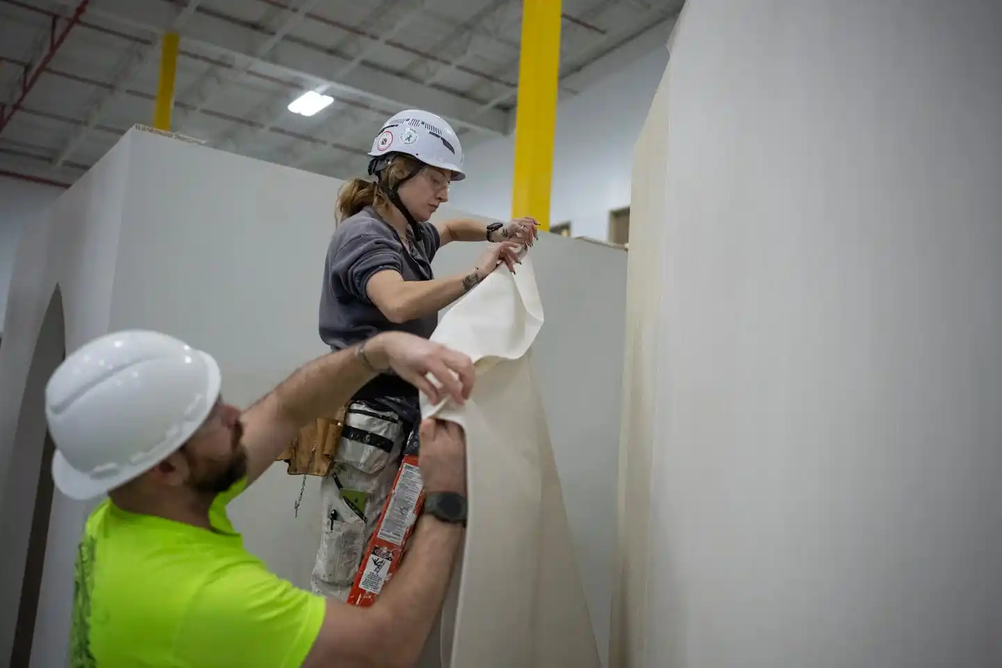 Instructor Keith Bailey helps student Kasity Benedict learn to hang wallpaper and vinyl at the Finishing Trades Institute.